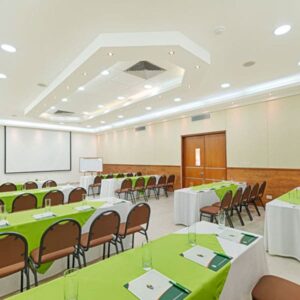 Salón Ónix corporativo del Hotel Arizona Suites Cúcuta, preparado para reuniones y eventos empresariales con mesas, sillas y proyector.