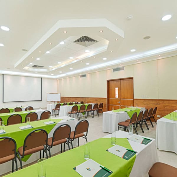 Salón Ónix corporativo del Hotel Arizona Suites Cúcuta, preparado para reuniones y eventos empresariales con mesas, sillas y proyector.
