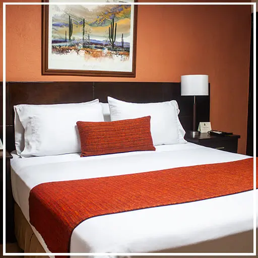 “Habitación del Hotel Arizona Suites Cúcuta con cama matrimonial, decoración moderna y ambiente acogedor.